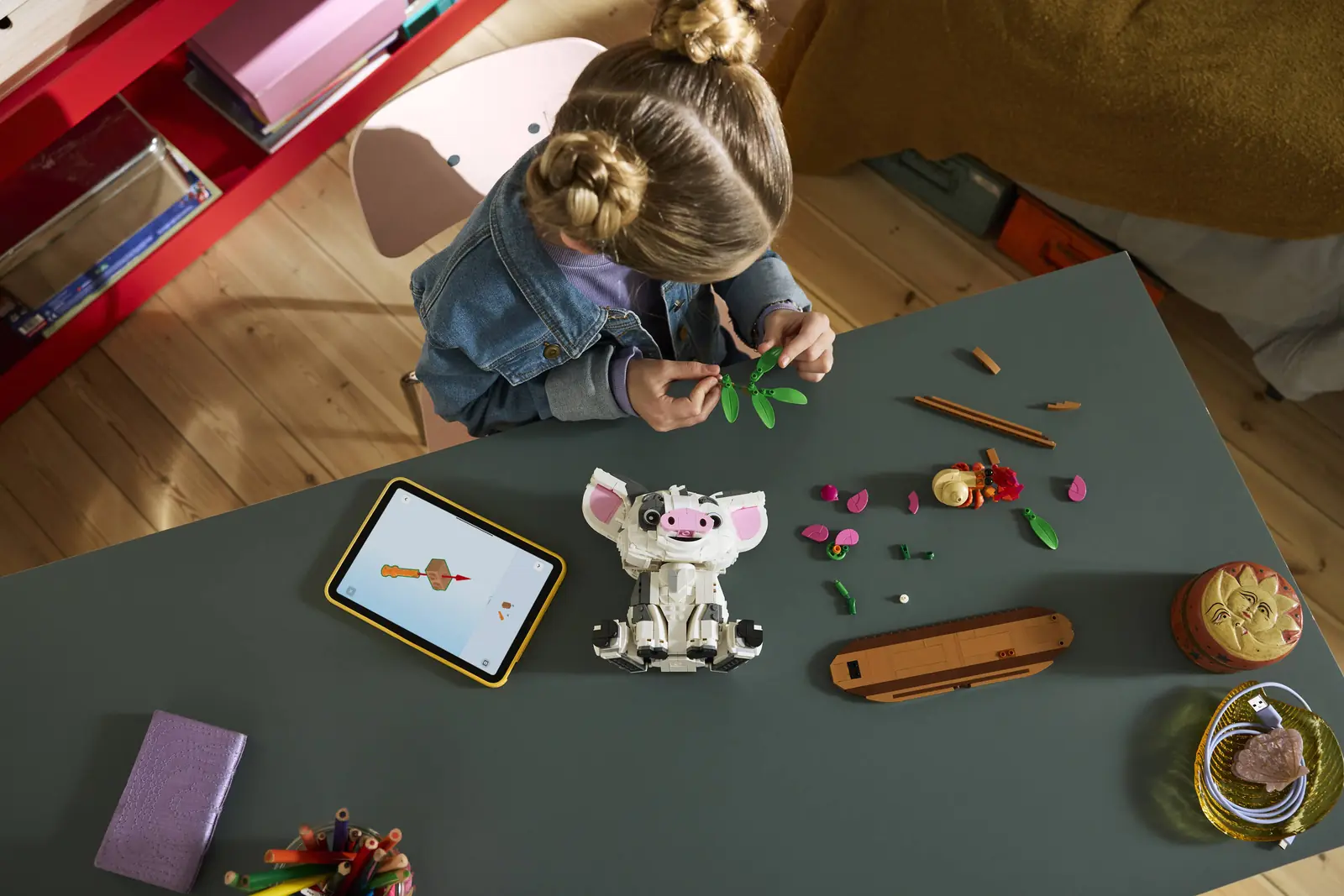 Nina construyendo el set LEGO Disney Pua 43292 con las instrucciones de LEGO Builder en una tablet