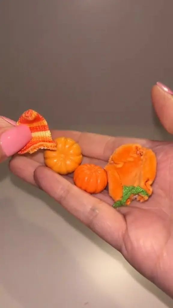 Gorro de punto y calabazas en miniatura de Pumpkin Patch sobre una mano