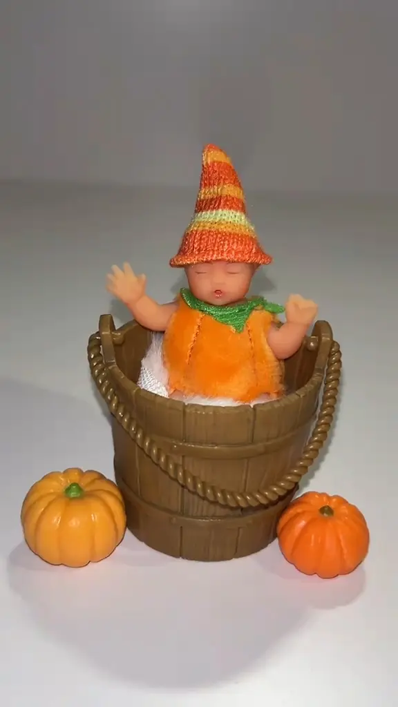 Foto real de coleccionista del bebé Pumpkin Bucket de My Mini Baby con su gorro cónico dentro del cubo de duelas