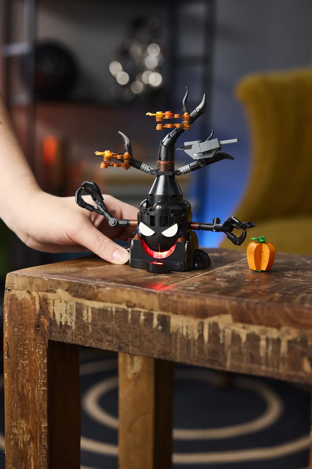 Mano pulsando el botón trasero del LEGO 40900 Terrorífico Árbol Embrujado con la boca iluminada en rojo