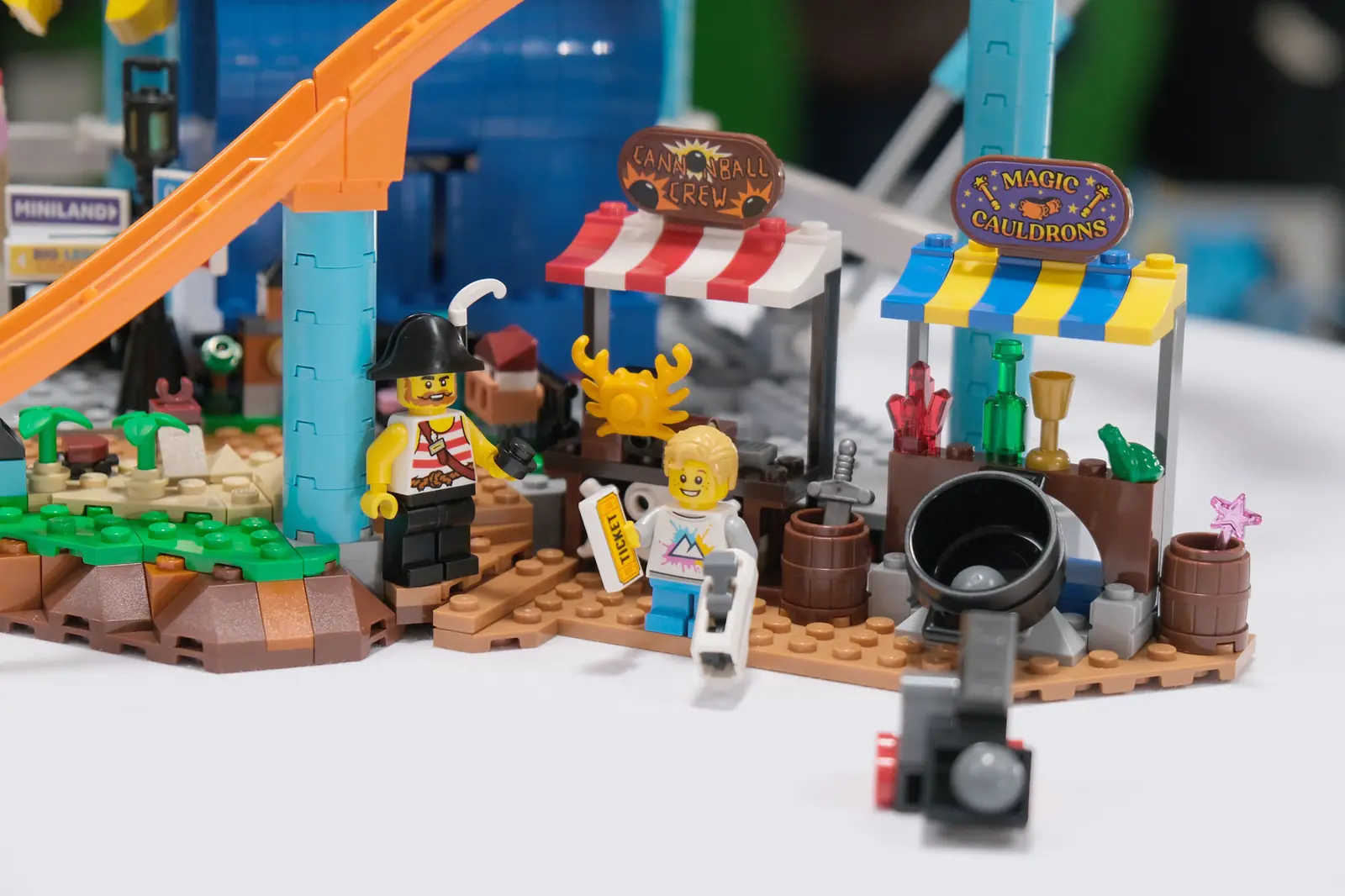 Detalle de los puestos de premios del LEGO 50090, con el cartel Magic Cauldrons, un caldero, un pirata y un niño con un ticket