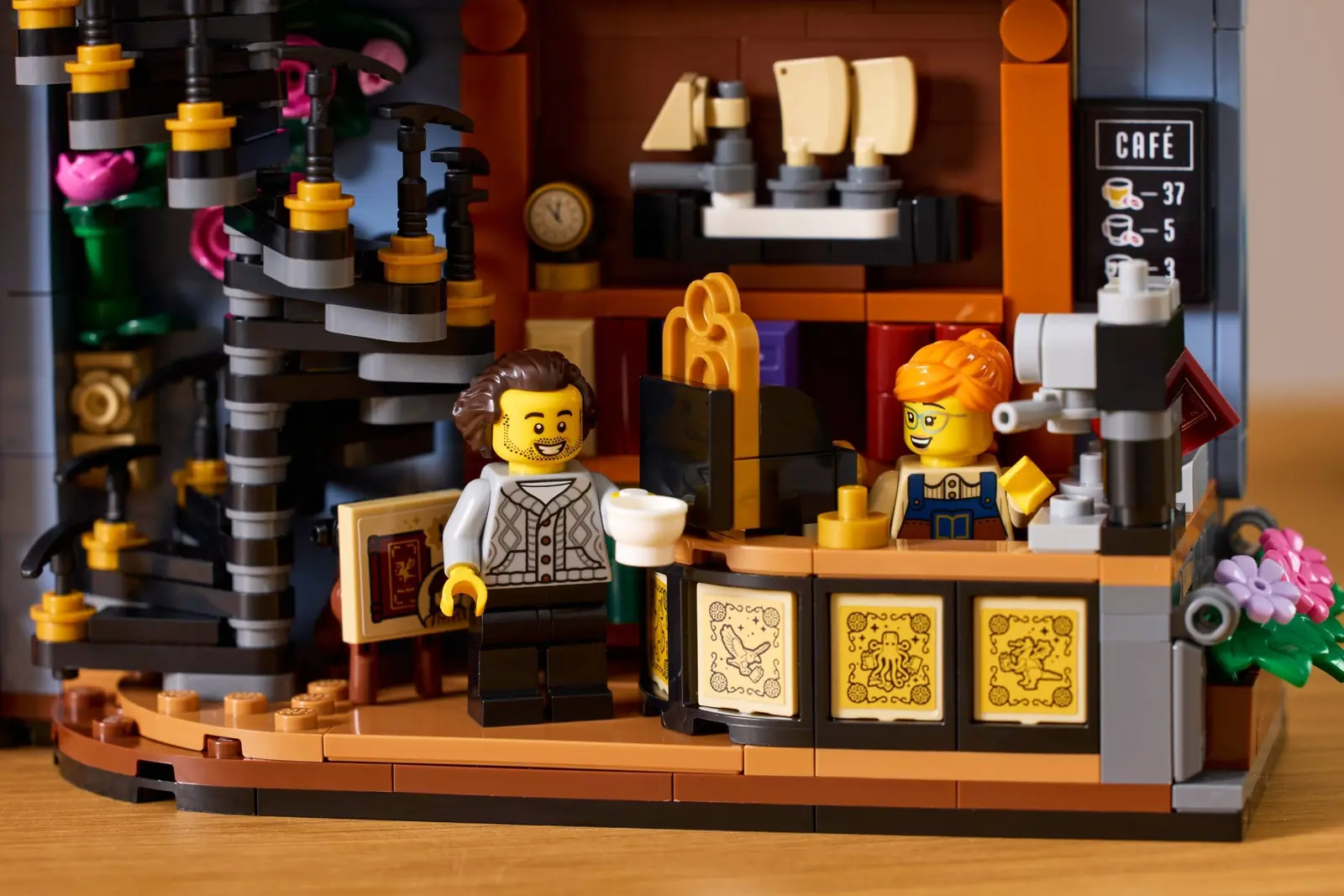 Las dos minifiguras del LEGO 11379 en la cafetería de la librería, una con un café junto al mostrador curvo y la pelirroja detrás