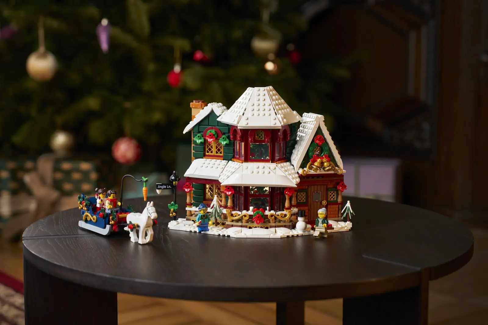 LEGO 11387 Holiday House montado sobre una mesa redonda con un árbol de Navidad real al fondo