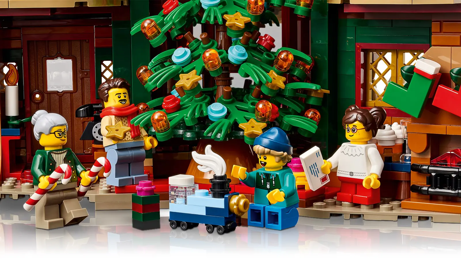 Las cuatro minifiguras del LEGO 11387 Holiday House junto al árbol de Navidad, con regalos y un trenecito de juguete