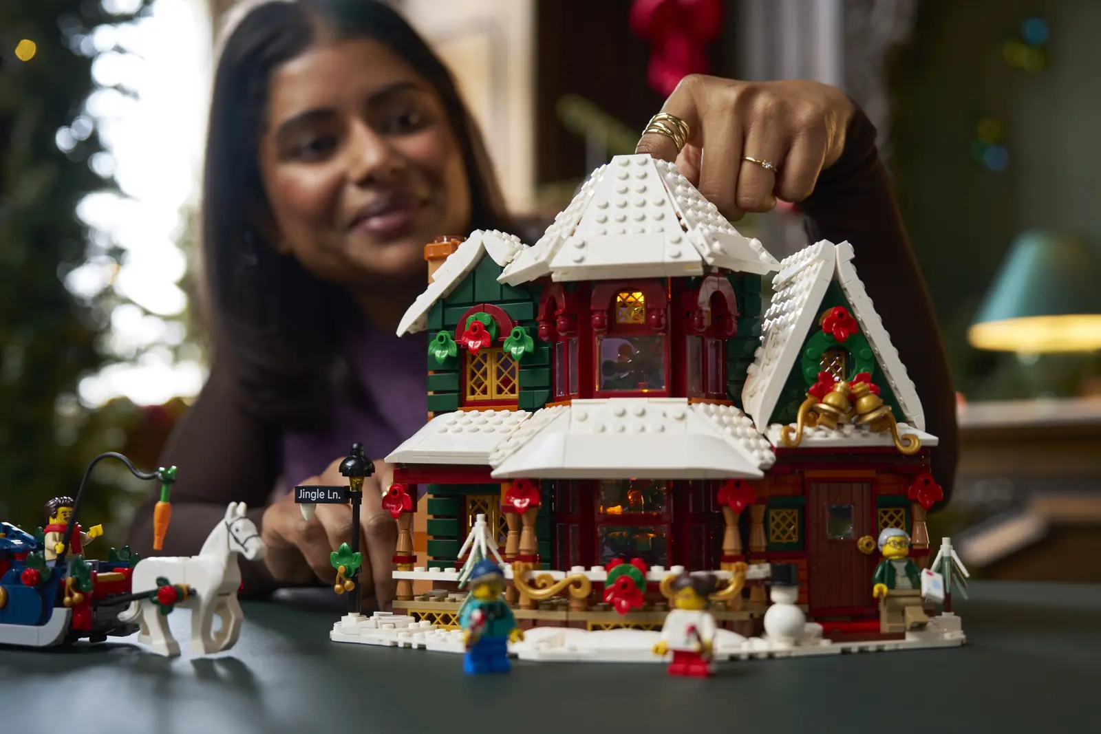 Persona retocando el tejado nevado del LEGO 11387 Holiday House montado sobre una mesa