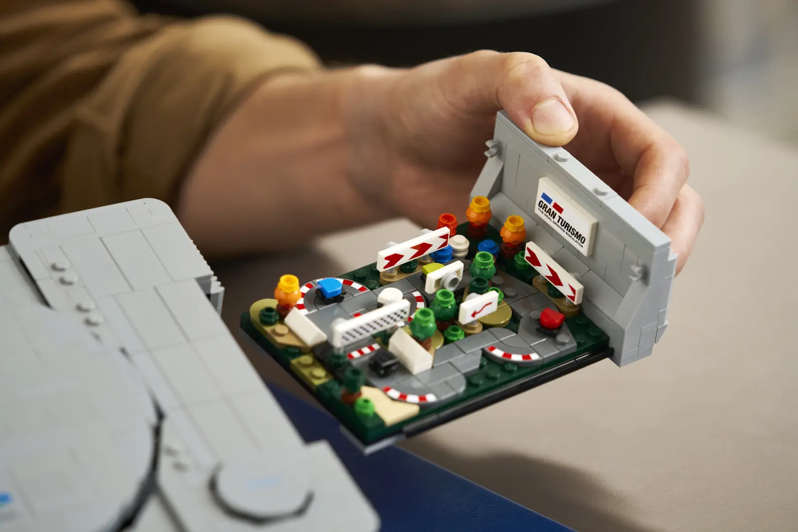 Diorama de Gran Turismo del set LEGO PlayStation 72306 saliendo entero de la consola sujeto con la mano