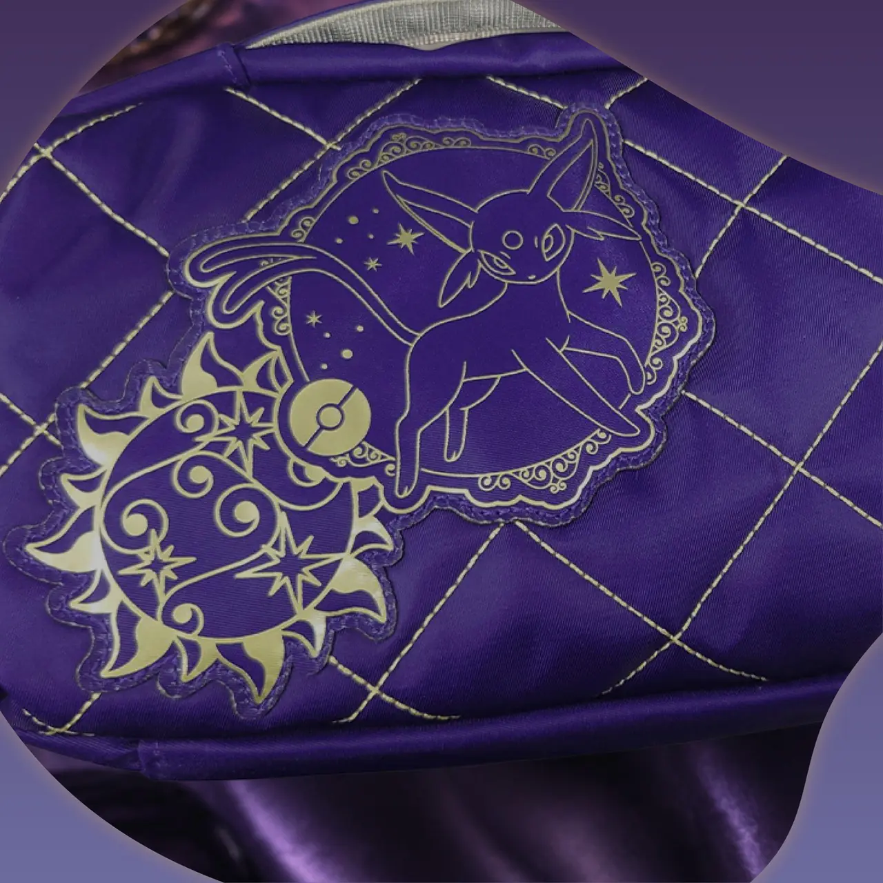 Detalle de la cara trasera de la funda HORI: parche de Espeon con el sol dorado sobre el acolchado morado