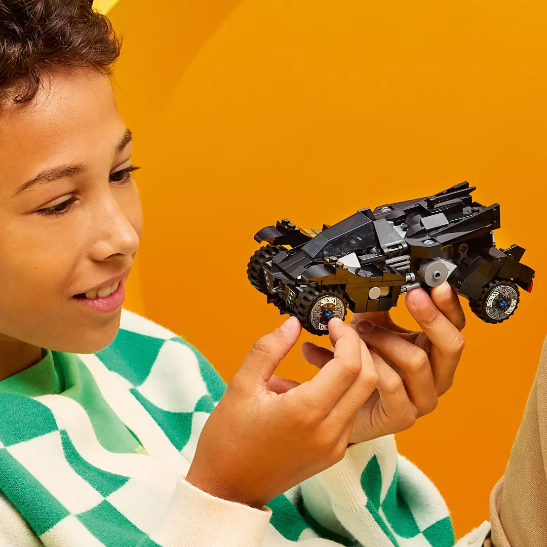 Un niño sostiene el Batmóvil de Arkham Batman LEGO 67009