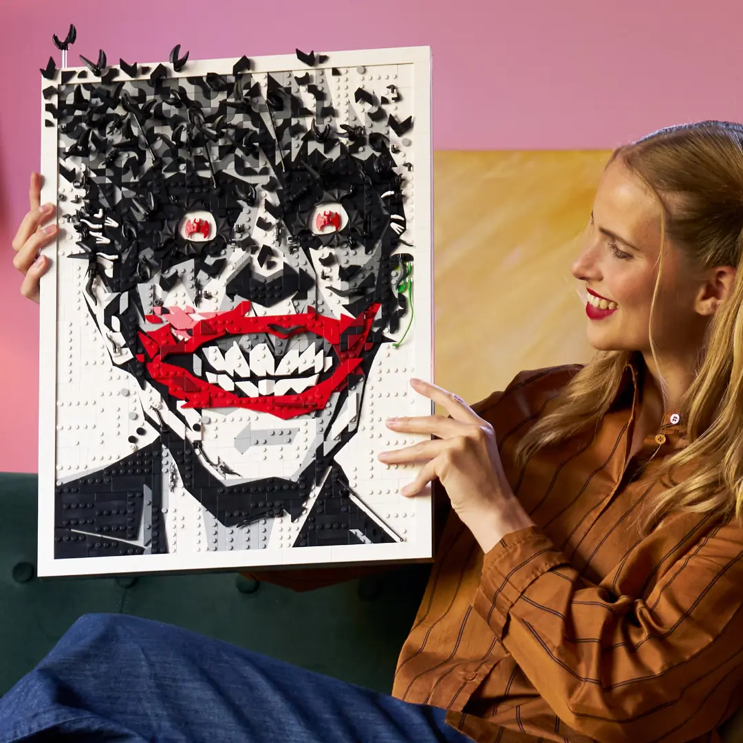 Una persona sostiene el arte mural LEGO 67012 del Joker para mostrar su tamaño